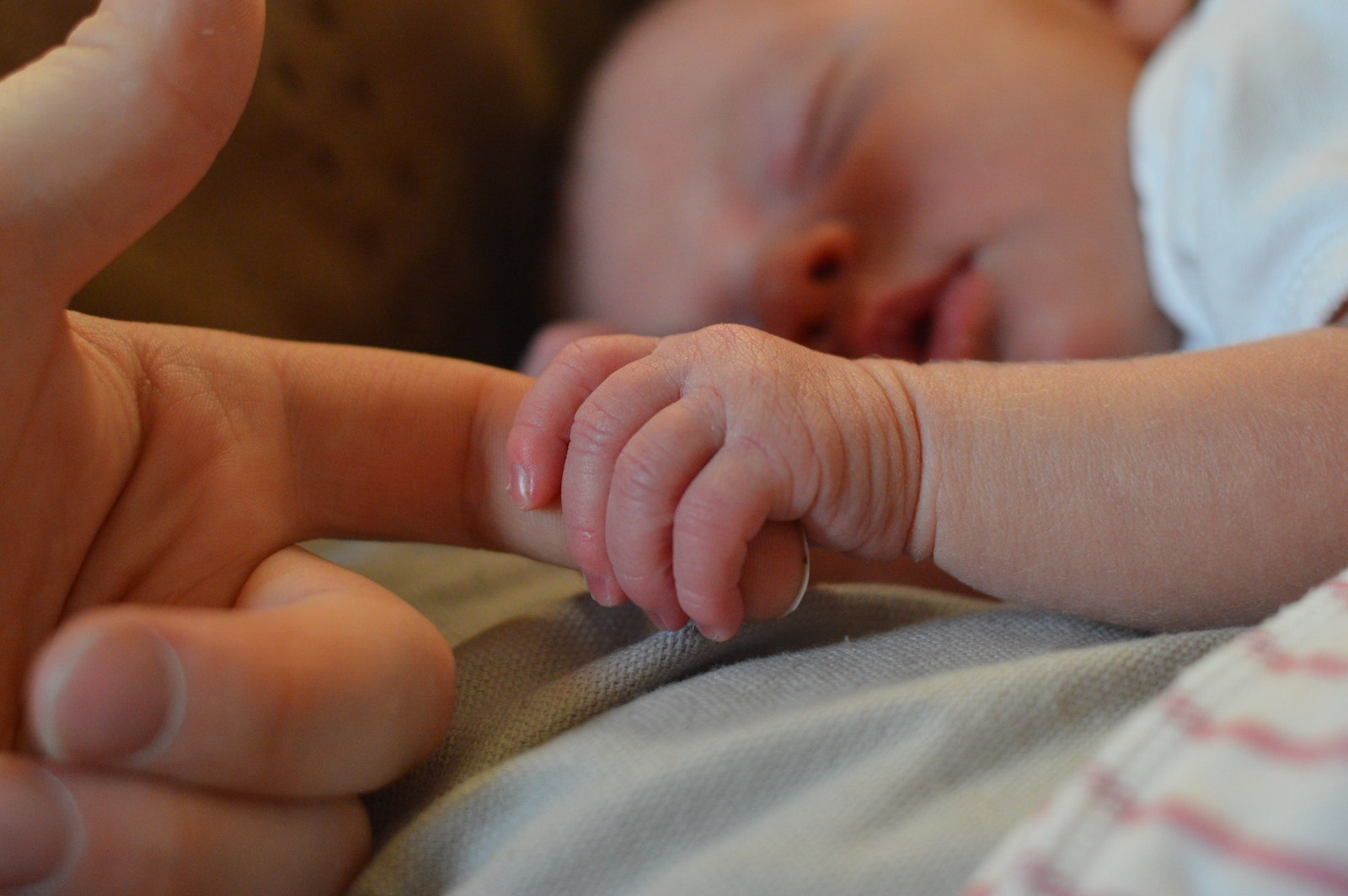 Sleeping baby holding new mom's hand