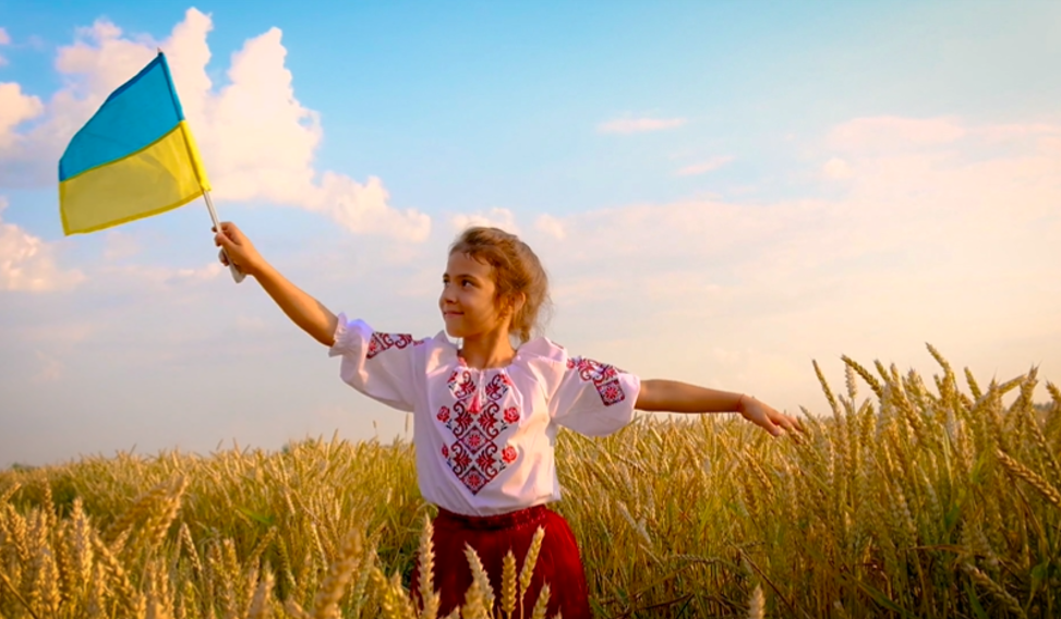 Girl with Ukraine flag in a field