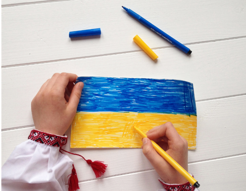 A child drawing Ukrainian flag with pencil crayons