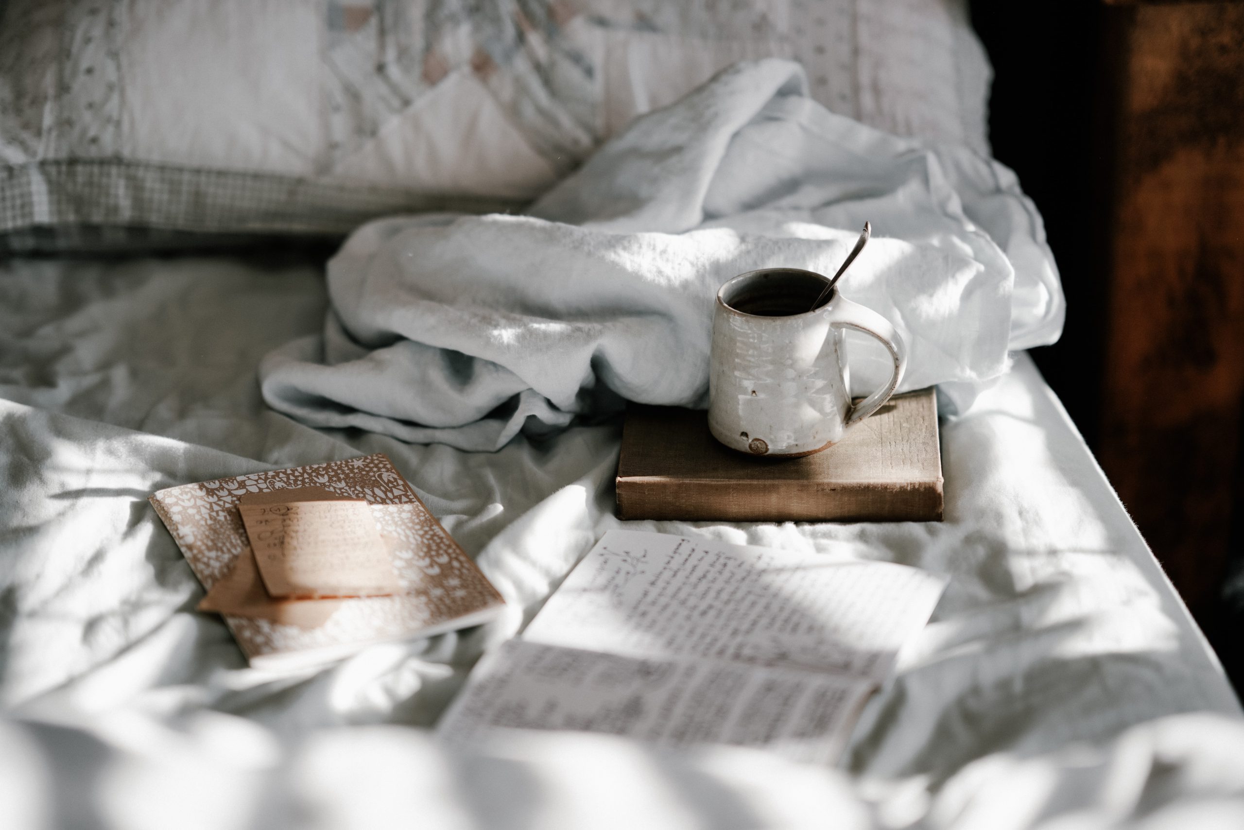 relaxing scene of a bed with an open journal and some tea